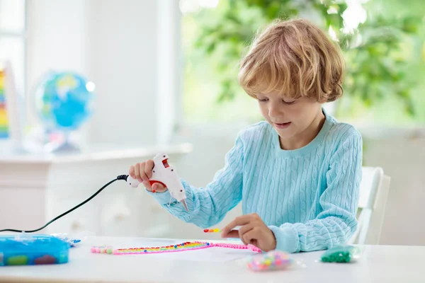 子供のための工芸品 グルーガンを持った子供 虹のデザインにボタンやビーズを付着創造的な小さな男の子 学校や幼稚園での芸術と創造性のクラス 楽しい死のプロジェクトを持つ就学前の子供 — ストック写真