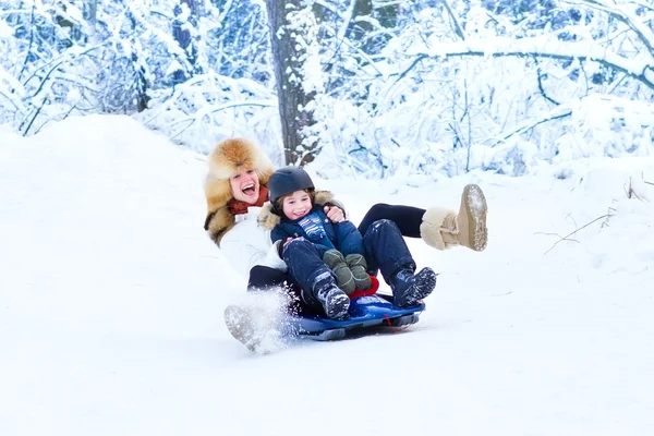 Matka a syn si pochutnávají na saních jezdit na krásný zimní den — Stock fotografie