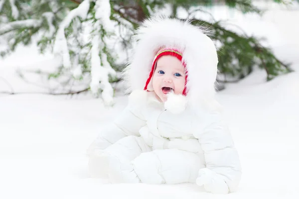 Adorable laughing baby sitting in snow under a Christmas tree — Stock Photo, Image