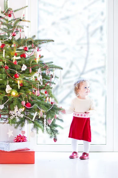Adorable toddler girl in a warm knitted dress decorating a beaut — Stock Photo, Image