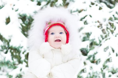 bir Noel ağacı yanında oturan sıcak beyaz ceket sevimli gülümseyen bebek kız
