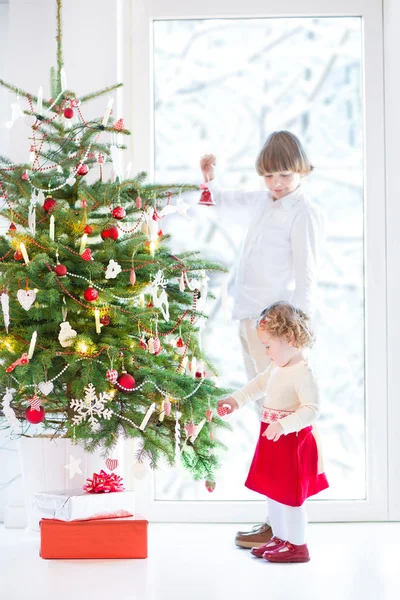 Κορίτσι όμορφο μικρό παιδί βοηθά τον αδελφό της να διακοσμήσει ένα χριστουγεννιάτικο δέντρο — Φωτογραφία Αρχείου