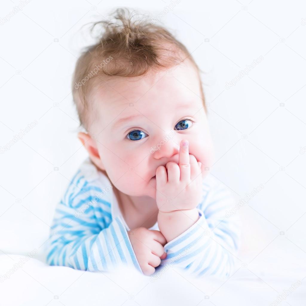 Sweet baby in a blue shirt sucking on its finger