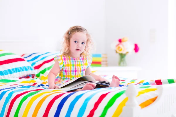 读一本书躺在床上的小女孩 — 图库照片