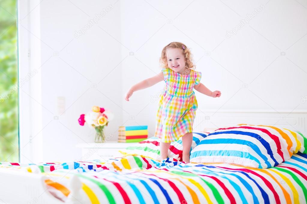 Little girl jumping on a bed