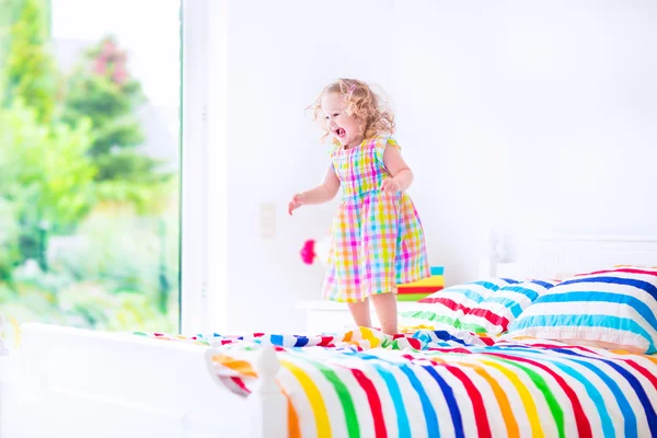 Klein meisje springen op een bed — Stockfoto