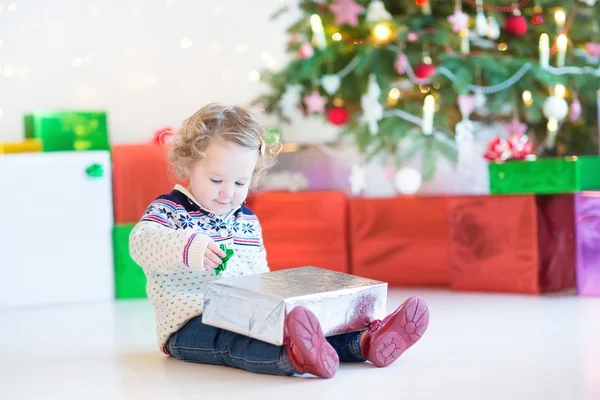 Portrait of a cute curly toddler girl opening Christmas present — Stock Photo, Image