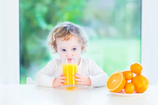 Adorable toddler girl drinking orange juice in the morning — Stock Photo, Image