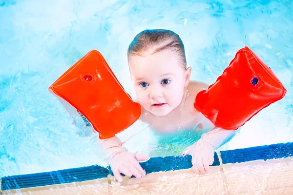 Ładny malucha zabawy w basenie, Noszenie czerwonymi opaskami — Zdjęcie stockowe