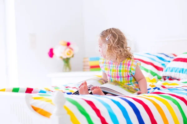 Kleines Mädchen liest im Bett ein Buch — Stockfoto