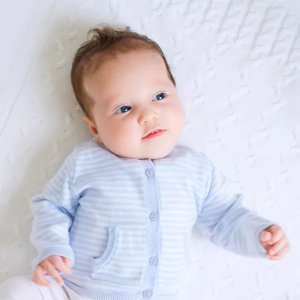 Newborn in white and blue on a white blanket — Stock Photo, Image