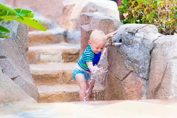 Baby boy playing with water tap outdoors — Stock Photo, Image