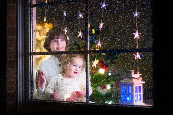 Enfants à la fenêtre la veille de Noël — Photo