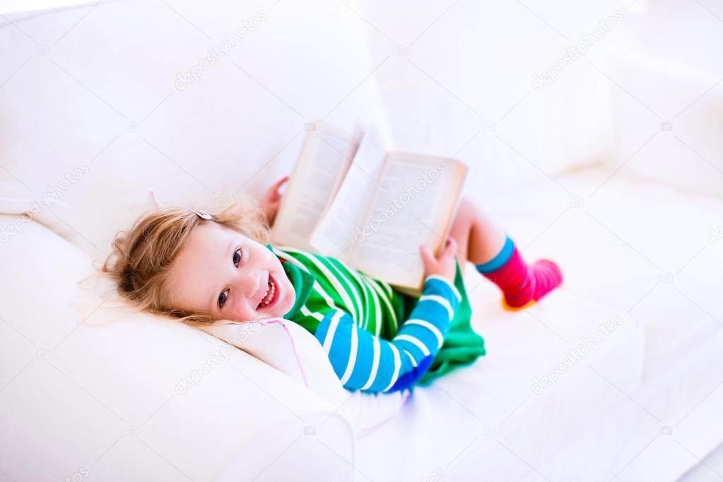 Little girl reading on a couch