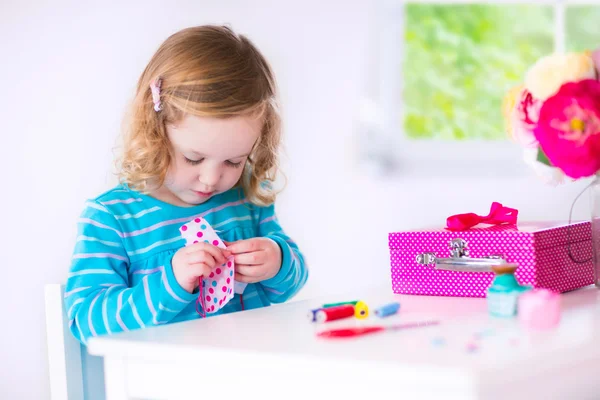 Kleines Mädchen näht ein Kleid für ihre Puppe — Stockfoto