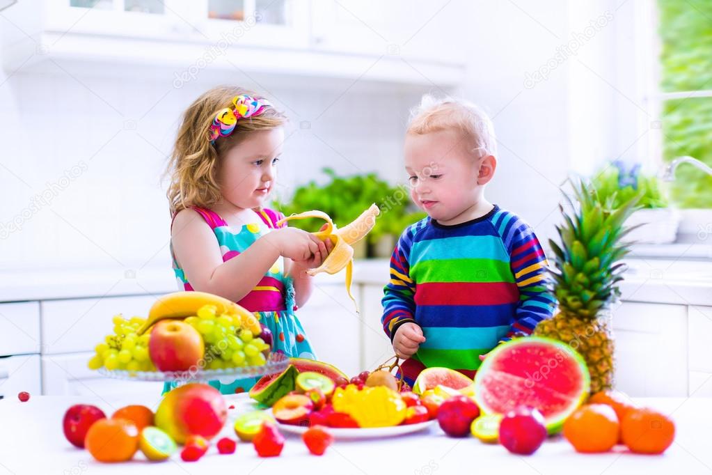 Kids eating fruit in a white kitchen