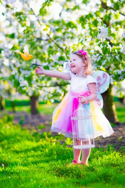 Niña en traje de hada alimentando a un pájaro — Foto de Stock