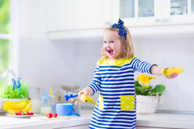 Küçük kız beyaz bir mutfakta kahvaltı hazırlarken