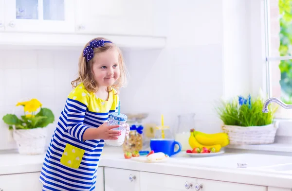 Lilla flickan förbereder frukost i ett vitt kök — Stockfoto