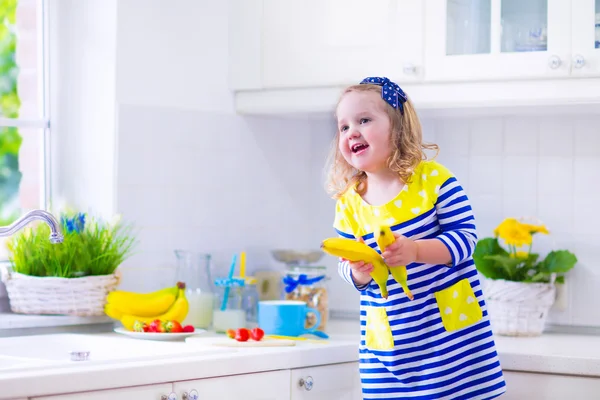 Lilla flickan förbereder frukost i ett vitt kök — Stockfoto
