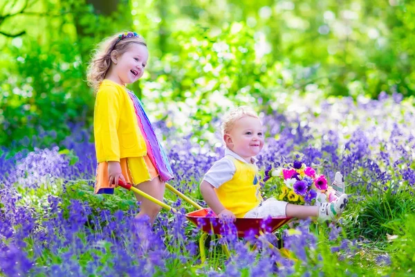 Kids in a garden with bluebell flowers — Stock Photo, Image