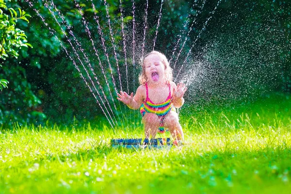 Little girl playing with garden water sprinkler — Stock Photo, Image