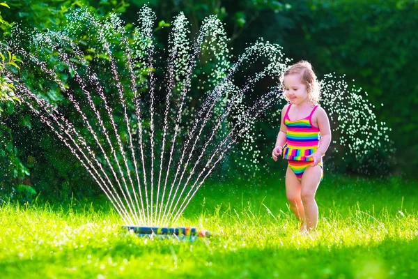 Meisje spelen met tuin water sprinkler — Stockfoto