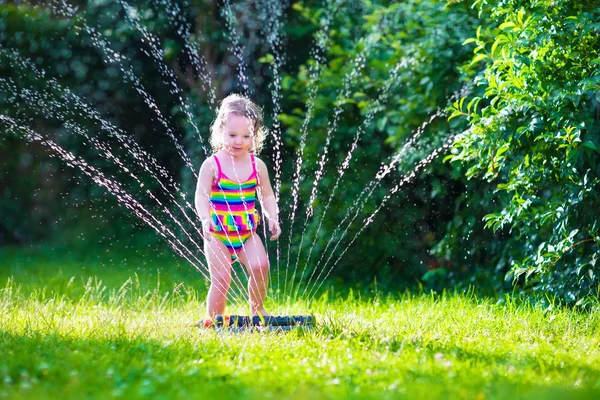 Kislány játszó kerti víz sprinkler — Stock Fotó