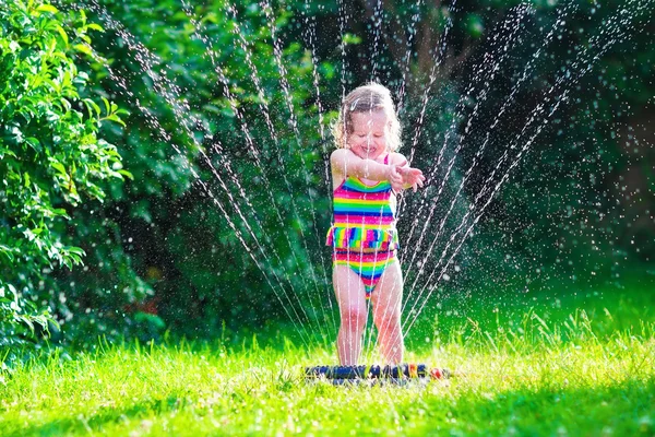 Menina brincando com aspersor de água do jardim — Fotografia de Stock