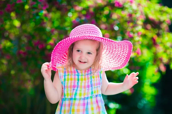 Liten flicka i en hatt i blommande sommar trädgård — Stockfoto