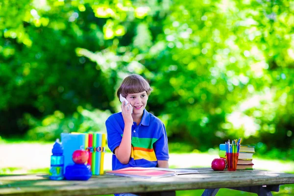 Child in school yard studying and talking on the phone — Stock Photo, Image