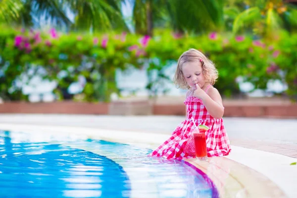 Маленькая девочка пьет сок в бассейне — стоковое фото