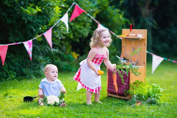 Kids playing with a toy kitchen in a summer garden — Stock Photo, Image