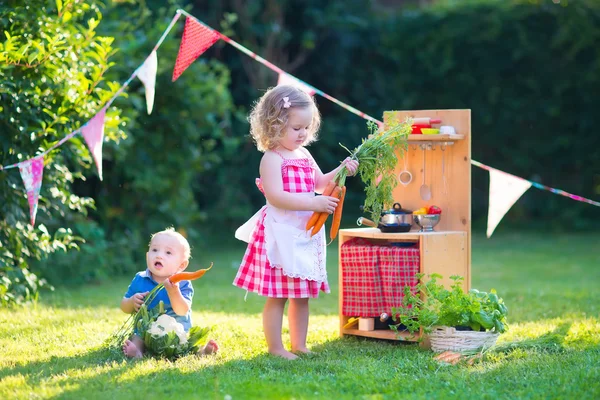 Barn som leker med en leksak kök i en sommarträdgård — Stockfoto