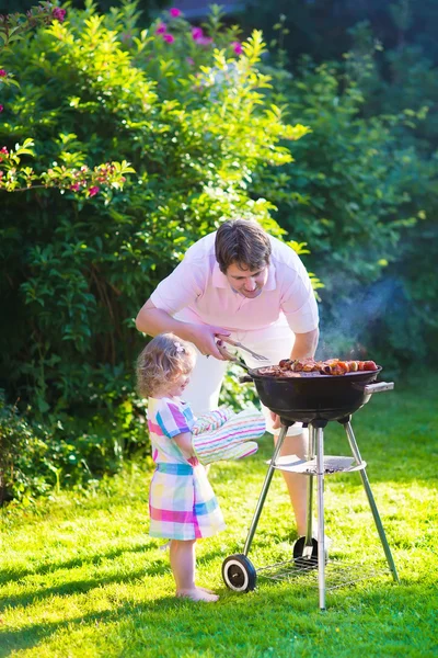Отец и дочь готовят мясо на гриле — стоковое фото