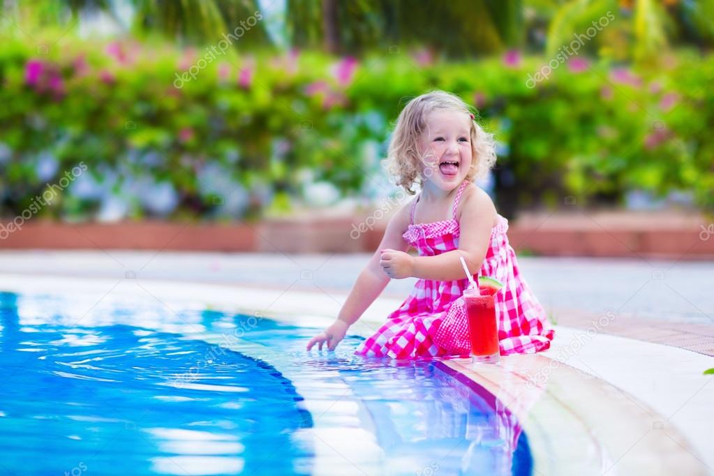 Little girl drinking juice at a swimming pool