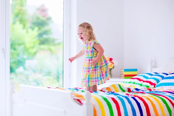 Klein meisje springen op een bed — Stockfoto