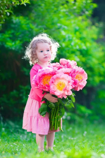 Petite fille avec des fleurs de pivoine dans le jardin — Photo