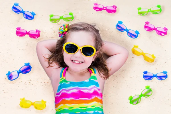 Bir plajda güneş gözlüklü küçük kız — Stok fotoğraf