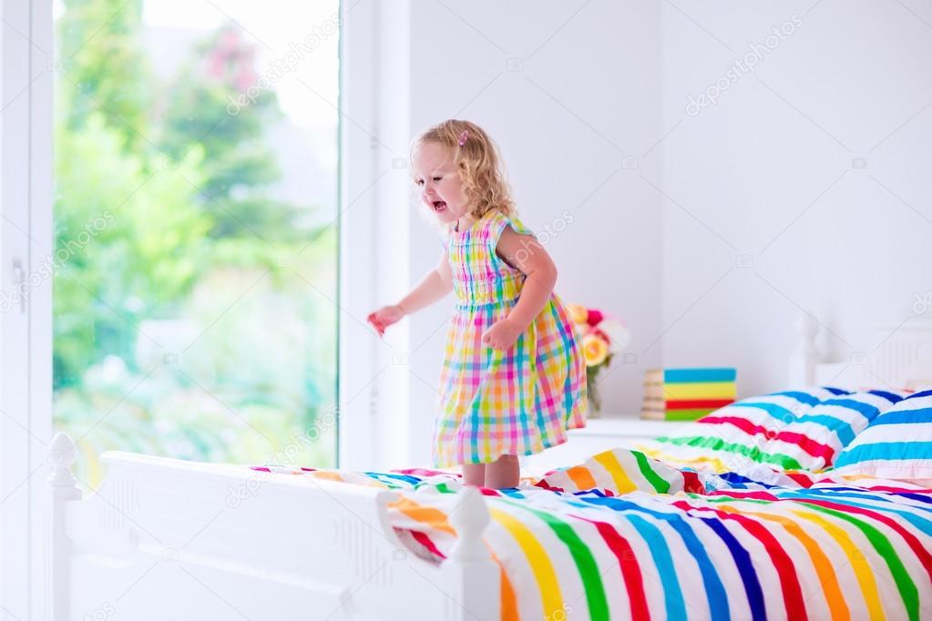 Little girl jumping on a bed