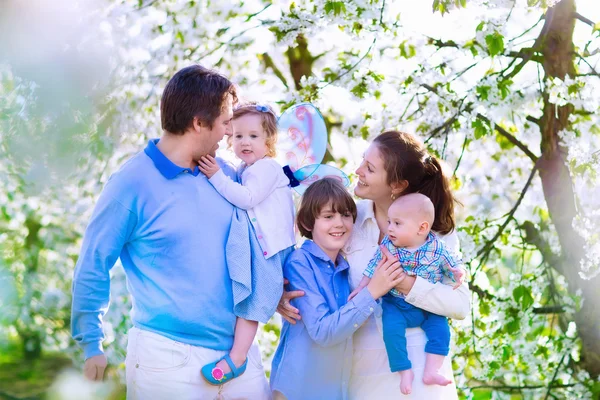 Счастливая семья в цветущем саду вишневого дерева — стоковое фото