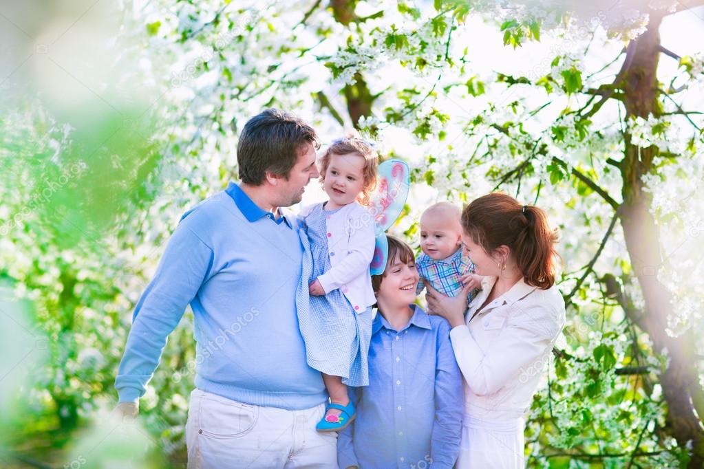 Happy family in a blooming cherry tree garden