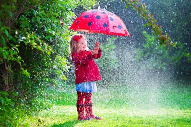 Little girl with umbrella playing in the rain