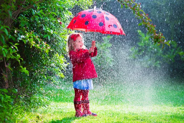 Niña con paraguas jugando bajo la lluvia — Foto de Stock