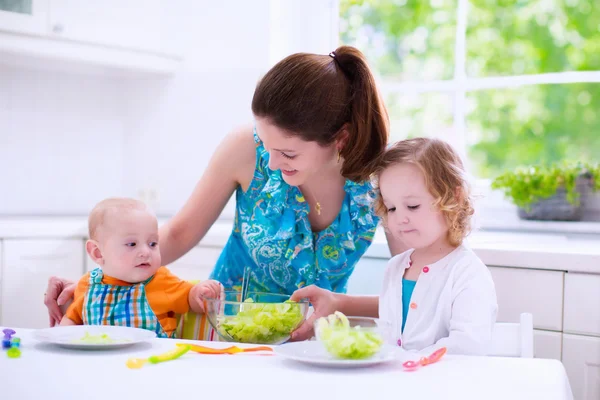 Mother and children cooking in a white kitchen — Stockfoto