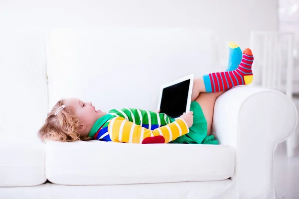 Little girl with tablet computer on a white couch — 图库照片