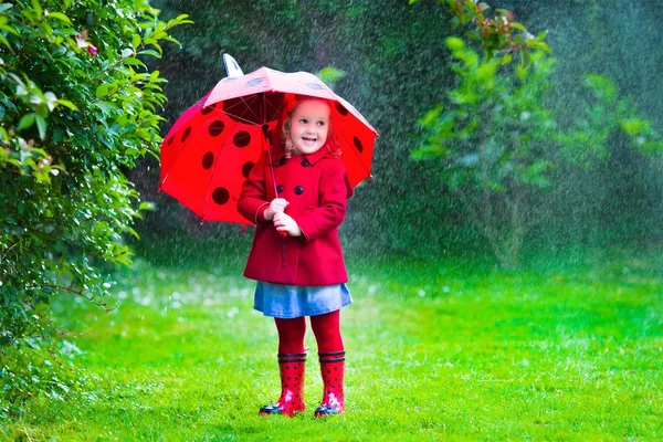 Little girl with umbrella playing in the rain — Stok fotoğraf