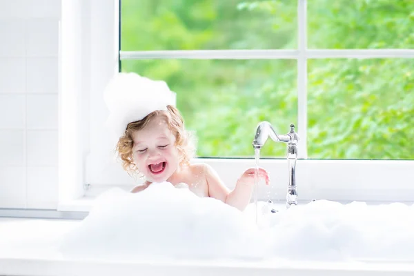 Baby girl taking bath with foam
