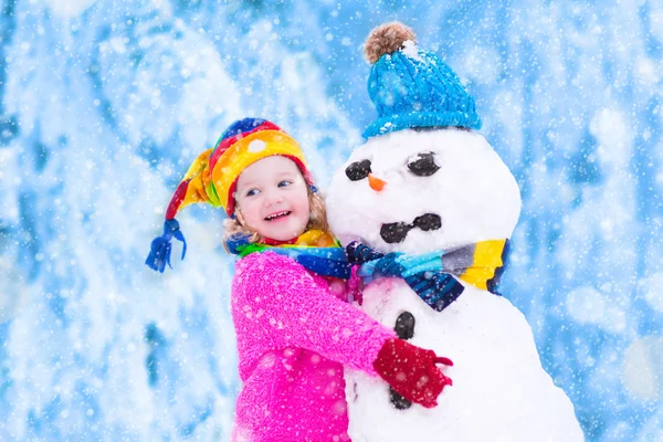 Meisje spelen met een sneeuwpop — Stockfoto