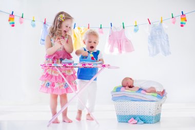 Kids ironing clothes for baby brother